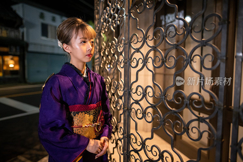 身着Furisode和服的年轻女子在“Seijin Shiki”成人礼之夜参观日本传统村庄